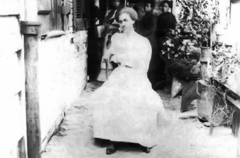 Old black and white photo of African American woman in white dress.