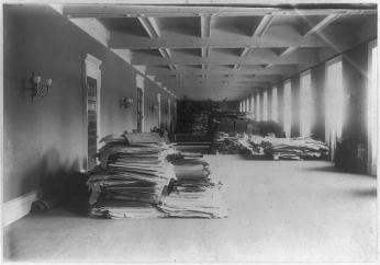 “Material removed from the Capitol and deposited in the north-basement hall, now occupied by the Music Division” (Photo Source: Library of Congress) Handy, Levin C, photographer. Material removed from the Capitol and deposited in the north-basement hall, now occupied by the Music Division. Washington D.C, 1897. Photograph. https://www.loc.gov/item/2007681328/.
