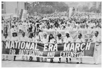 A group of demonstrators march with a large banner reading 