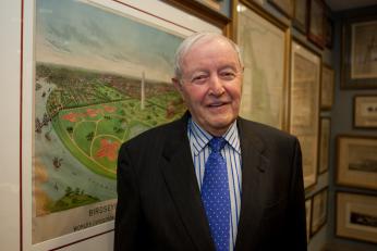 Albert Small in his later years. He stands in front of a  pairing of the National Mall/ 