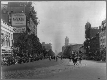 Soldiers walk down a street in DC. Crowds of people line either side of the street. Soldiers walk down a street in DC. Crowds of people line either side of the street.