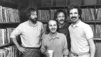 WHFS deejays Damian Einstein (far right) and Weasel (front) pose with musician Jesse Colin Young (second from right) and an unidentfied record executive (far left) at WHFS headquarters in Annapolis, MD in 1983.  (Photo source: Handout photo/Steve King).
