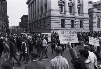 Protests outside of the Baltimore courthouse, focusing in on a sign that says "Berrigan a black sheep in the priesthood." (William Morgenstern, [War and draft protest], 1968. Gelatin silver print. University Archives, University of Maryland, Baltimore County, UARC Photos-09-01-0034.)