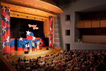 Capitol Steps Performance at the Ronald Reagan Building and International Trade Center in Washington, D.C. Stage with performers in the background and a seated audience in the foreground
