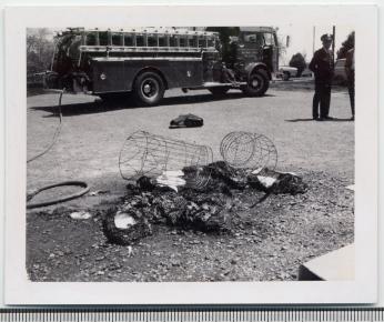 After the Catonsville Nine action, the wire basket sits overturned with the ashes of draft files sitting there. (Source: Baltimore Library, Catonsville Branch)