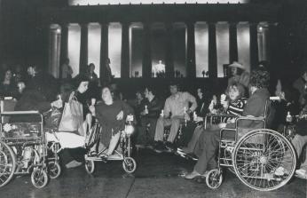 Disability rights advocates hold an all-night vigil outside of the Lincoln Memorial on May 3, 1977. (Reprinted with permission of the DC Public Library, Star Collection © Washington Post) A black-and-white photo. A large group of people gathered in front of the Lincoln Memorial, it is dark outside. Most of the people in the foreground are sitting in wheelchairs and holding candles.
