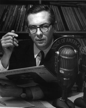 A young and serious Willis Conover, cigarette in one hand, jazz record in the other, in his Voice of America studio. Source: Wikimedia Commons