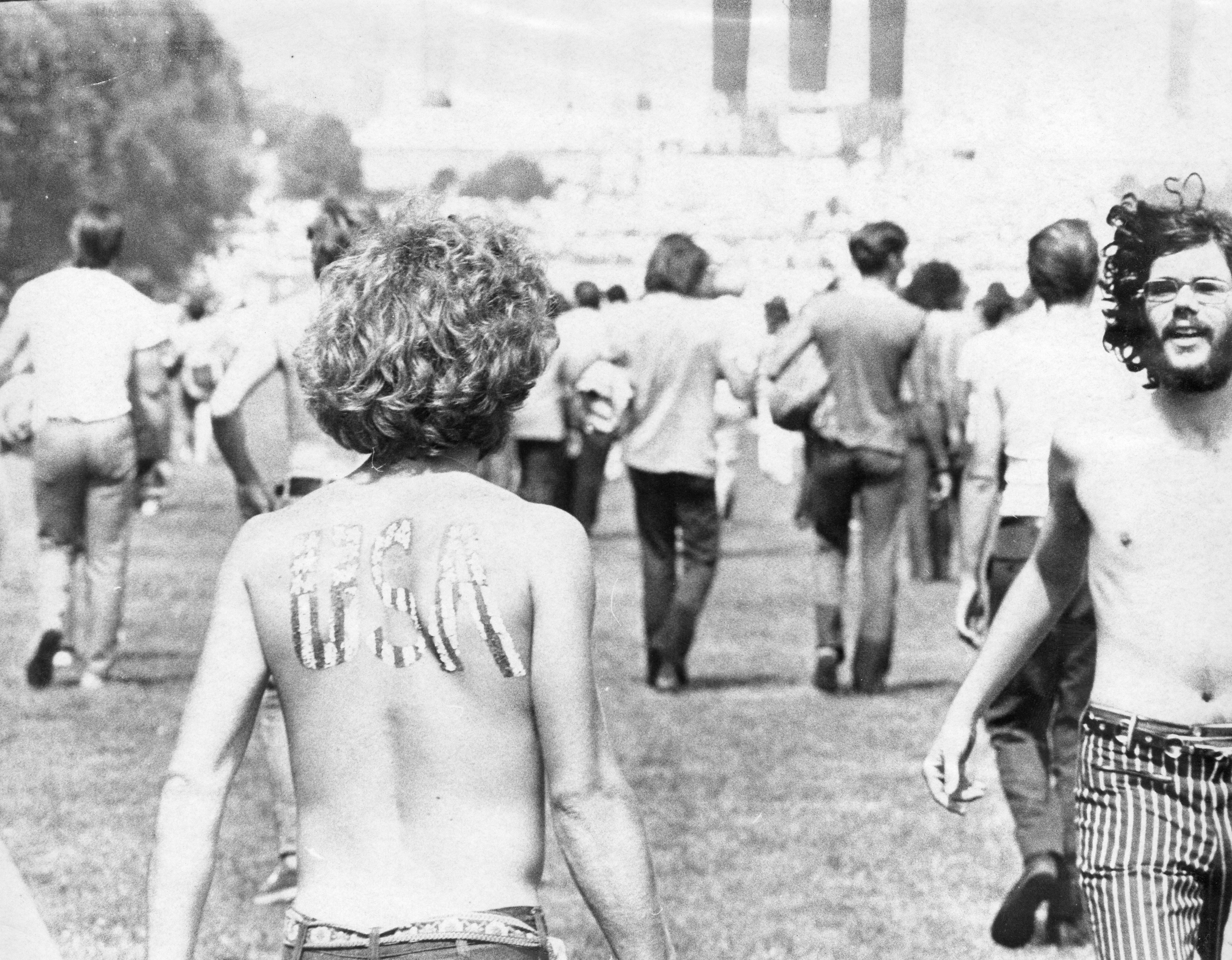A Hippie walks on the National Mall on Honor America Day with "USA" painted onto his back