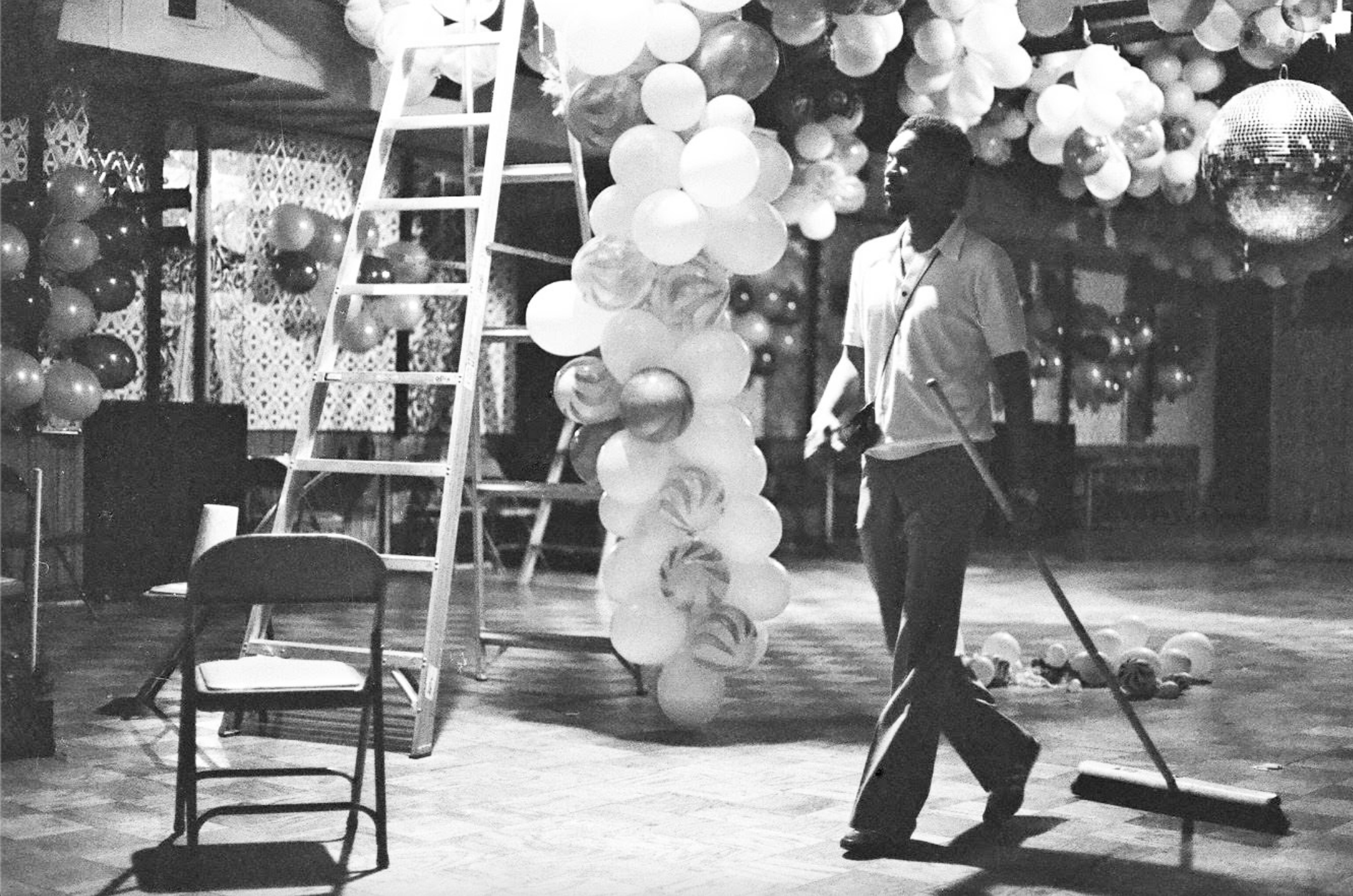 A ClubHouse staff person with a broom cleans up after a ClubHouse party. 