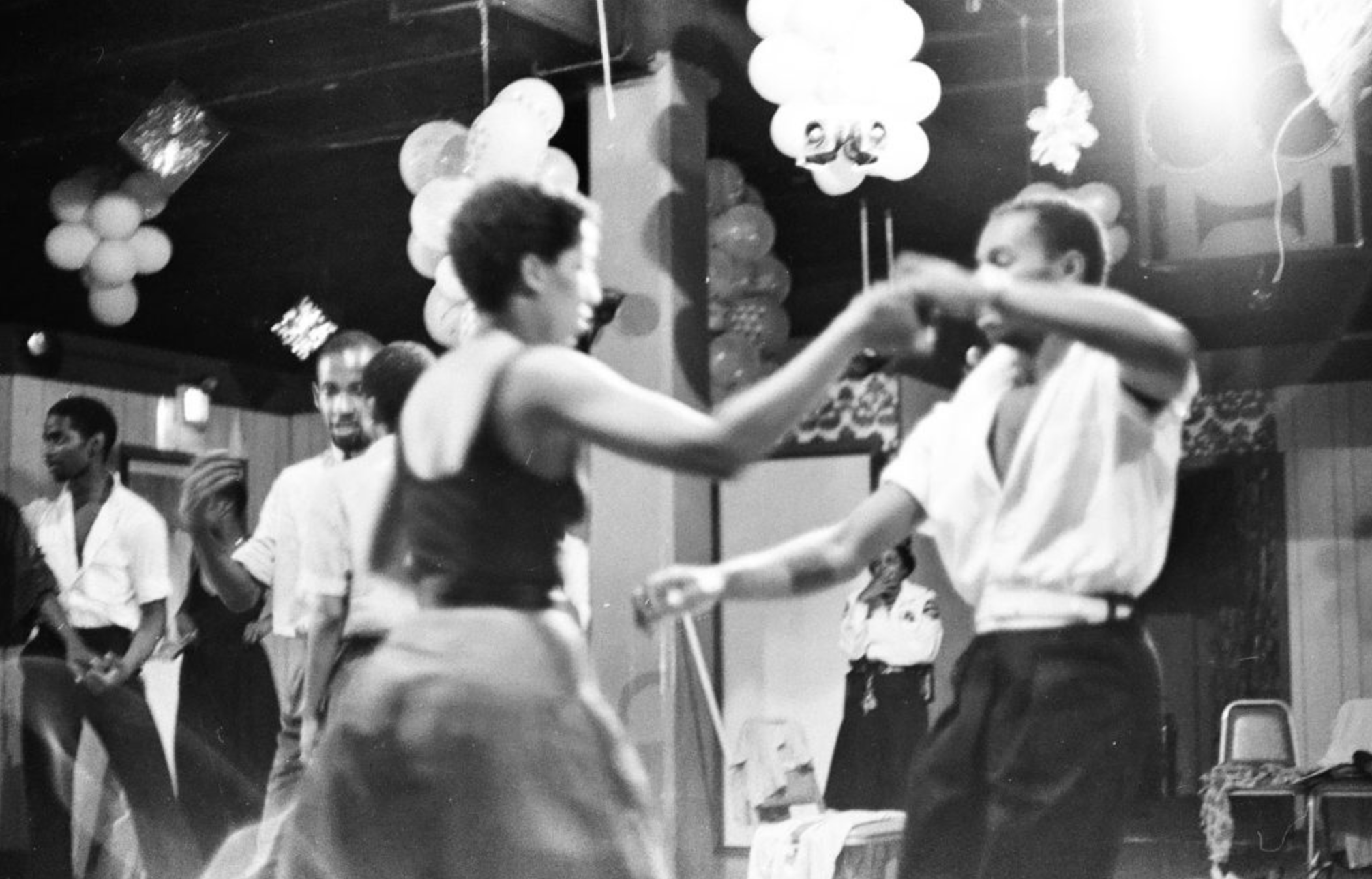 Two people dancing during a night at the ClubHouse, surrounded by party decorations and other attendees.