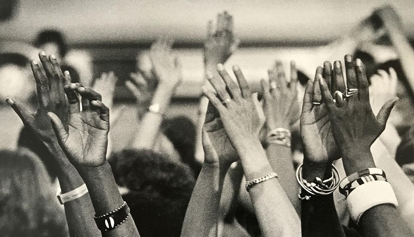 Black and white image of hands reaching up, taken at Sisterfire festival.