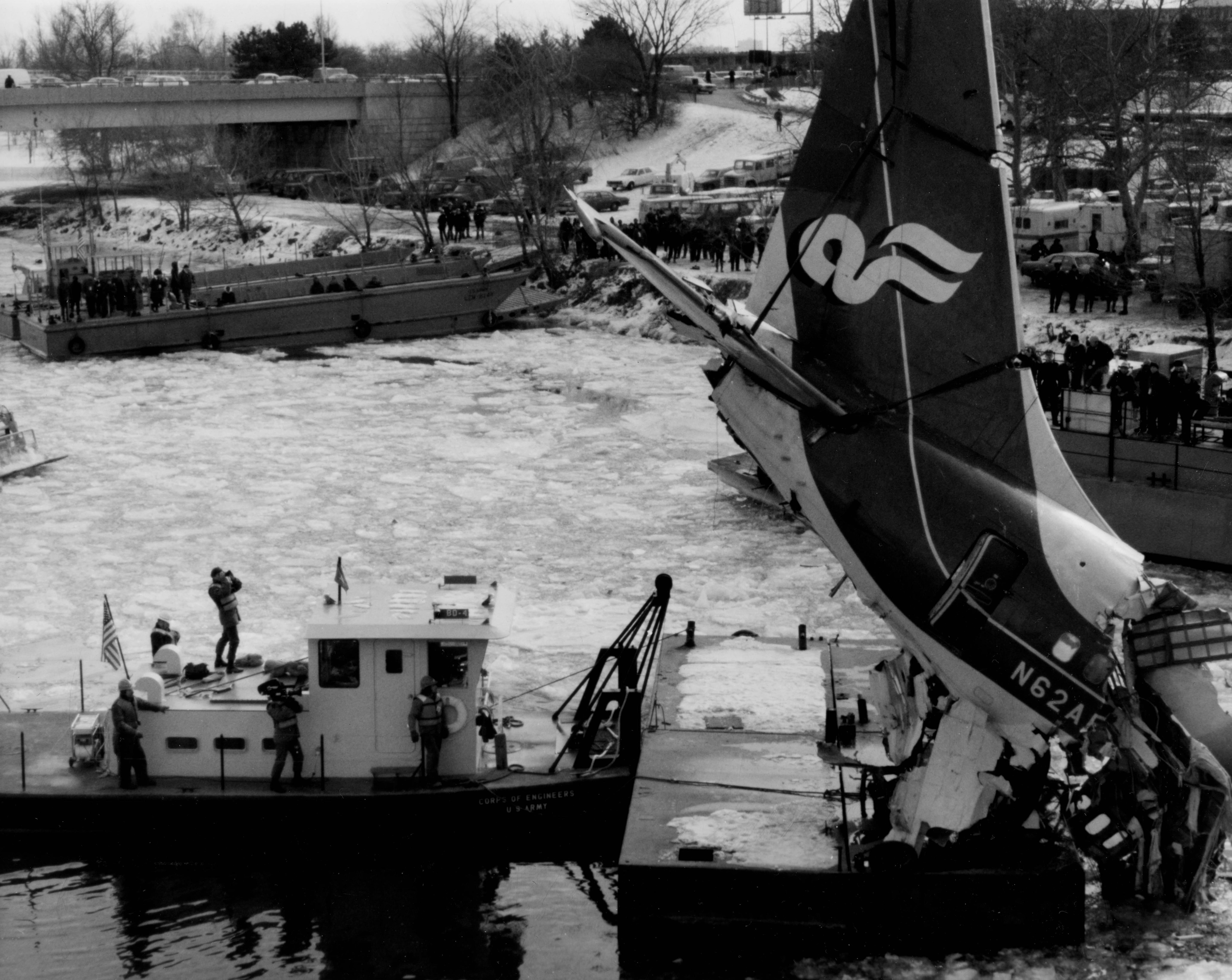 Tail section of wrecked Air Florida plane is lifted above boats on icy river.