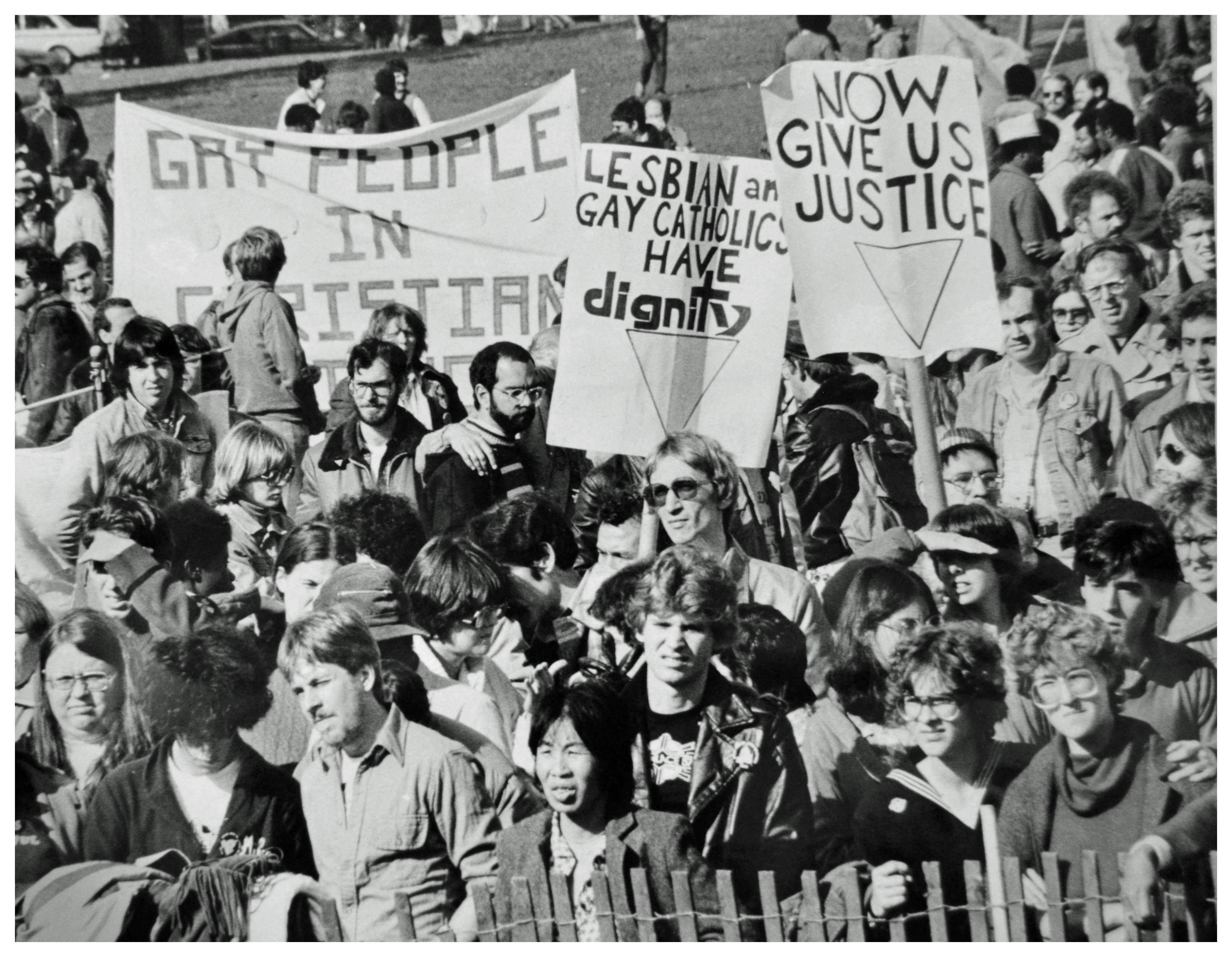 A group of people holding signs, including one that says "Now Give us Justice"