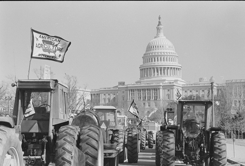 Tractors parked in front of US Capitol, one flying a flag reading "American Agriculture Movement"