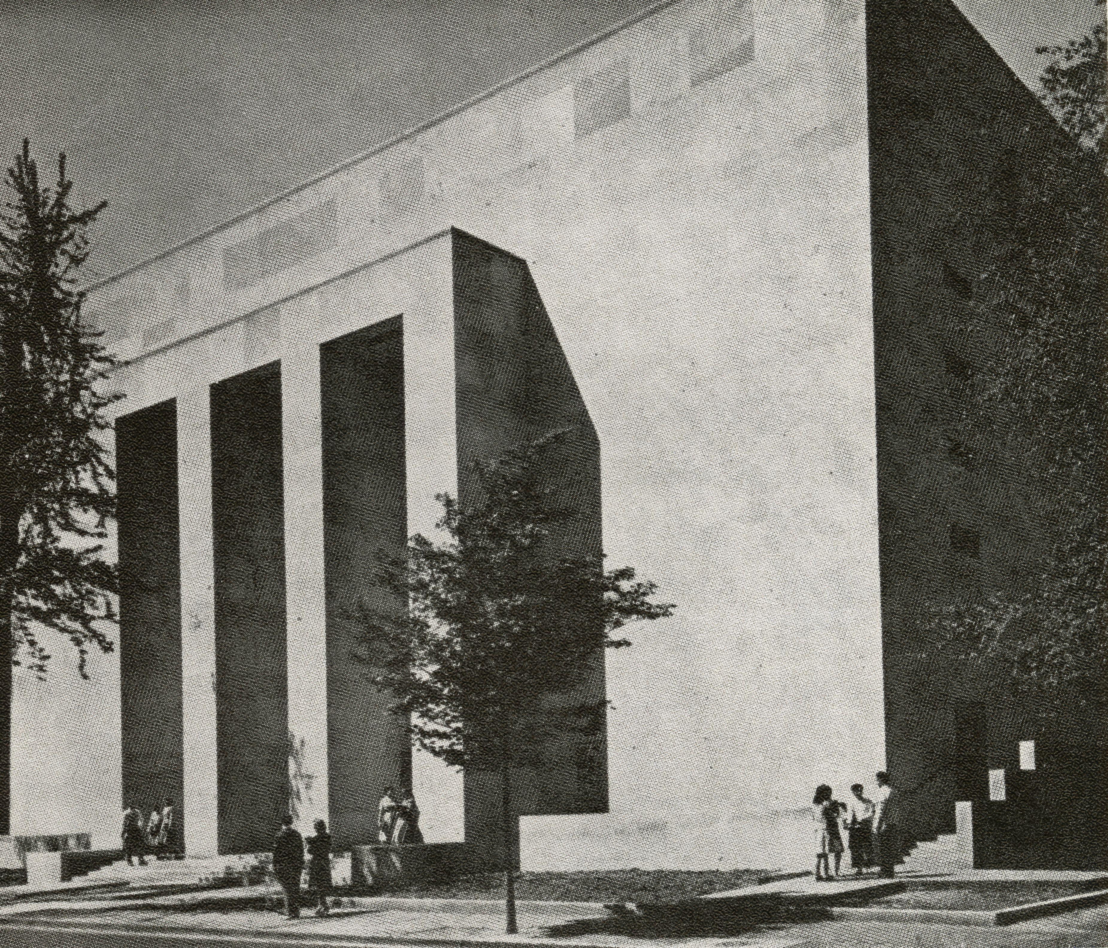 A back and white picture of Lisner Auditorium. It is taken from the right-hand adjacent corner of the street. The building has box columns at the front entrance.