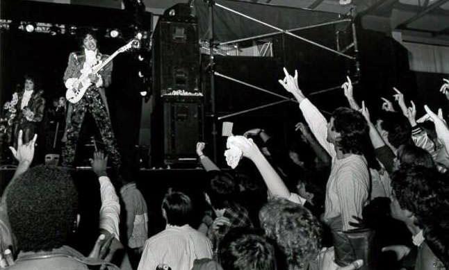 Prince on stage mid-performance, with the crowd throwing up "I Love You" signs. (Photo: Courtesy of the Gallaudet University Archives)